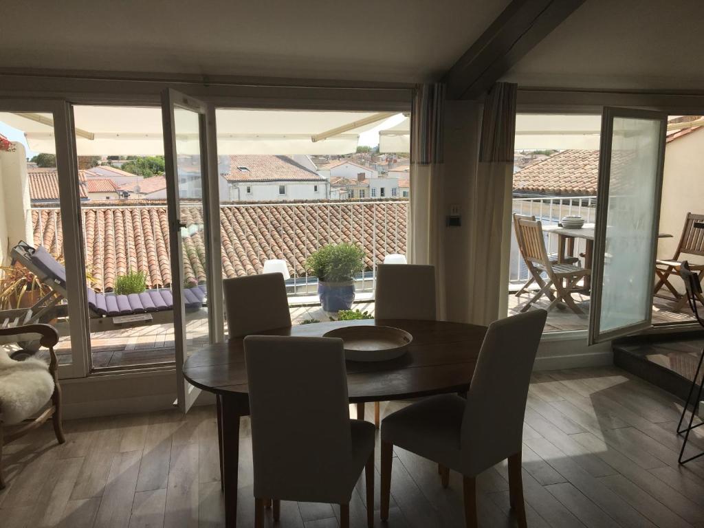 uma sala de jantar com mesa e cadeiras e uma varanda em La terrasse sur les toits em Saint-Martin-de-Ré