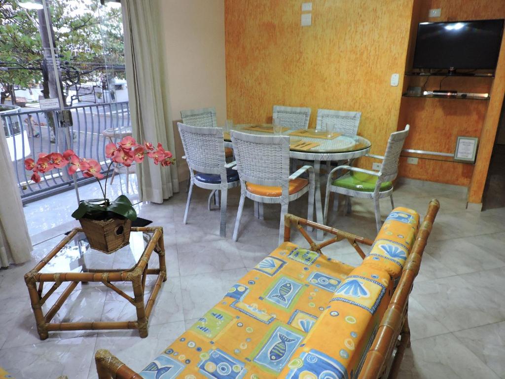 a living room with a couch and a table and chairs at Condomínio Baia Blanca in Guarujá