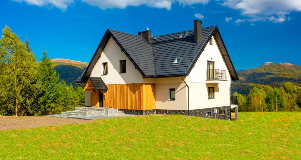 une maison avec un toit noir sur une colline verdoyante dans l'établissement Pod Wielką Zalesioną Górą, à Wetlina