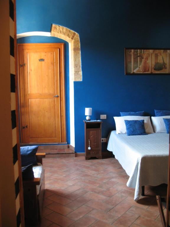 niebieska sypialnia z łóżkiem i drewnianymi drzwiami w obiekcie Locazione Turistica Totti w mieście San Gimignano