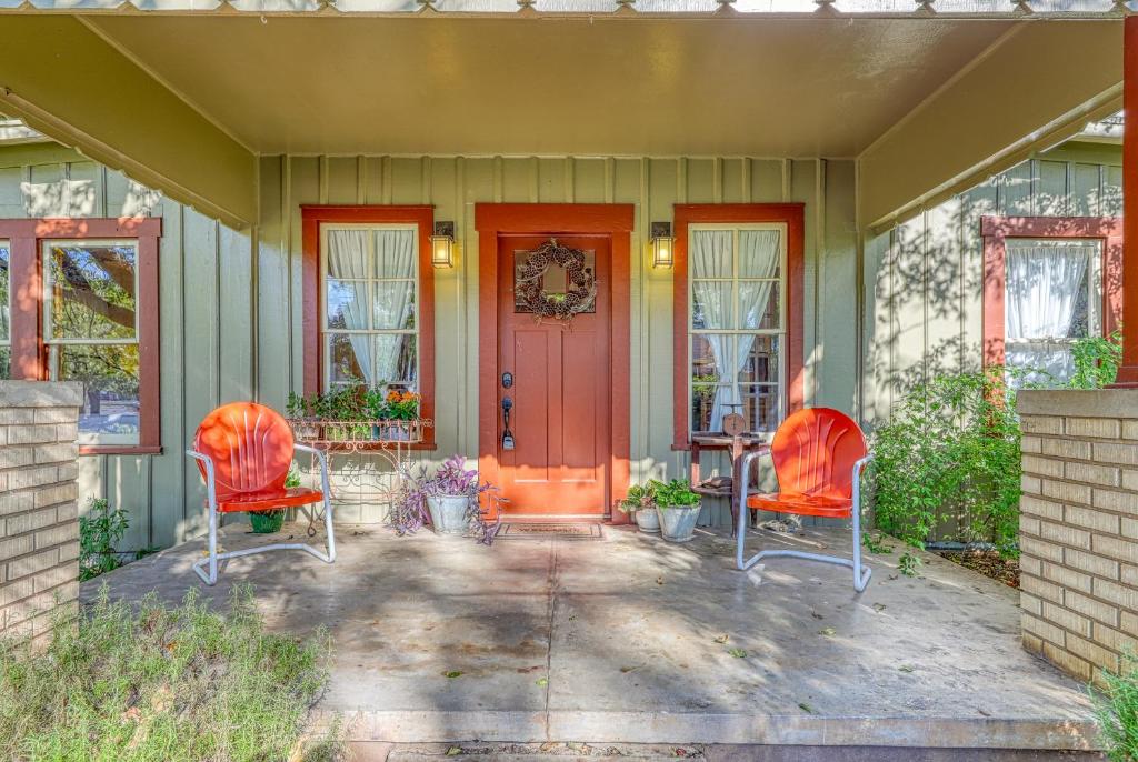 a house with two chairs and a red door at Cosmos Cottage in Fredericksburg