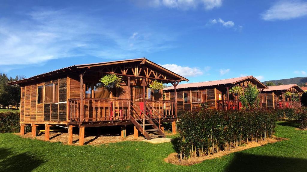 a large wooden cabin with a porch and a yard at CABAÑAS VILLA INES DE SUESCA in Suesca