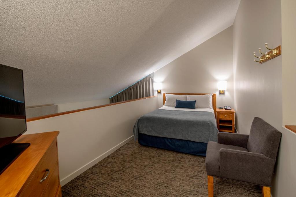 a hotel room with a bed and a chair at Whistler Village Inn & Suites in Whistler
