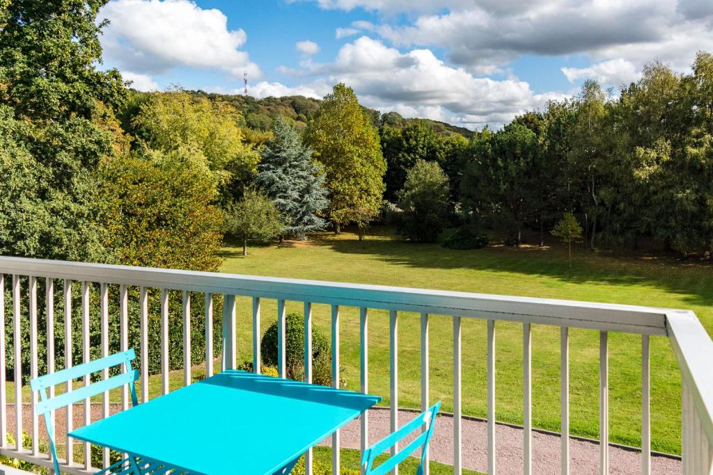 - Balcón con mesa azul y 2 sillas en Les charmes Du Bosquet Parc d'Amour et Nature Parking Privé Sécurisé en Étretat