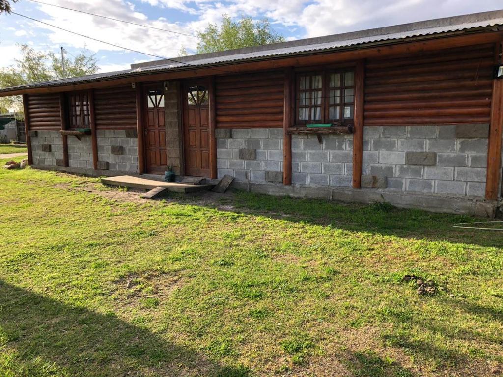 una cabaña de madera con un patio de césped delante de ella en hermosa cabaña cerca del puerto en San Clemente del Tuyú