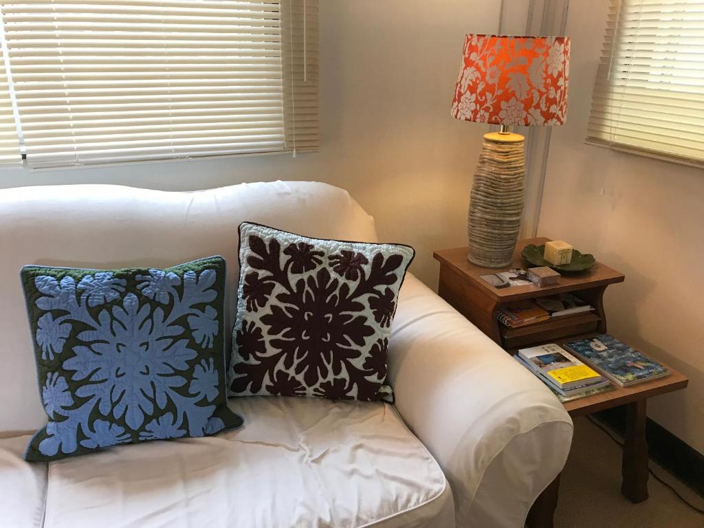 un sofá blanco con almohadas y una mesa con lámpara en Old American House K-113 en Ginowan