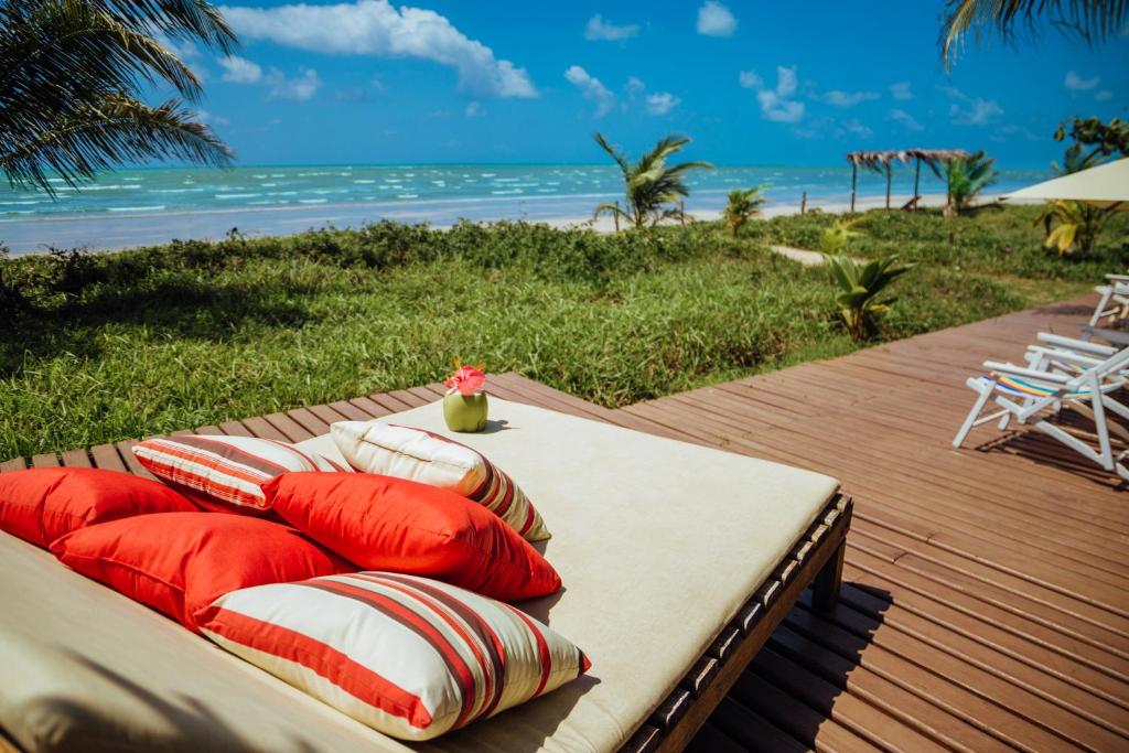 a table with pillows on a deck with the beach at Pousada Vila Sagui in Maragogi