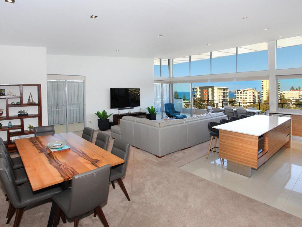 a dining room and living room with a table and chairs at Karmasea 43 in Alexandra Headland