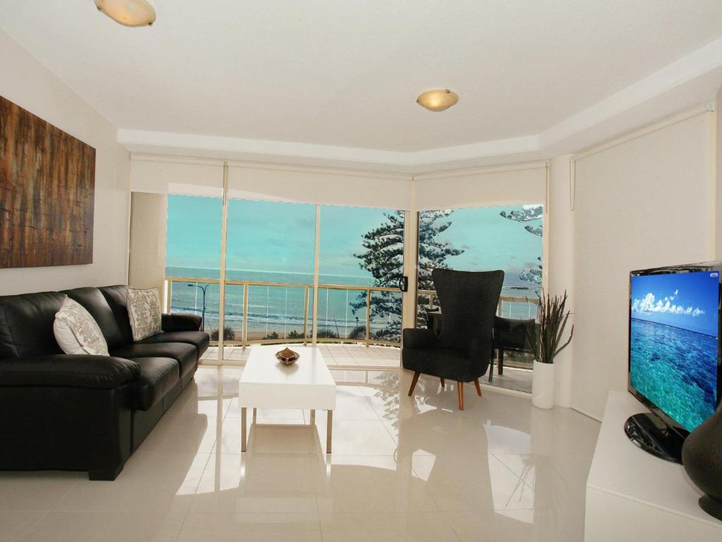 a living room with a black couch and a piano at Zanzibar 404, Sensational 2 Bedroom Oceanview Apartment in Mooloolaba