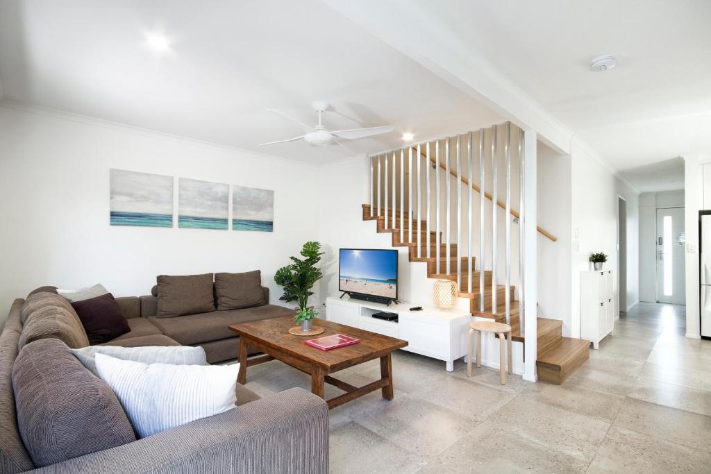 a living room with a couch and a table with a tv at The Islander Apartment 1, Noosa Heads in Noosa Heads