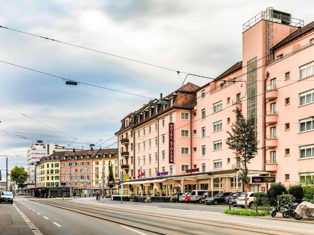 eine leere Straße in einer Stadt mit rosa Gebäuden in der Unterkunft Hotel Stoller in Zürich