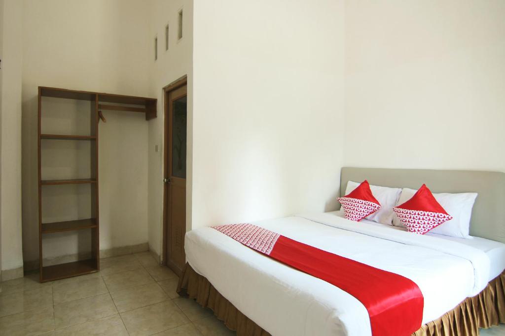 1 dormitorio con 1 cama grande con almohadas rojas y blancas en OYO 1456 Hotel Garuda, en Lampung