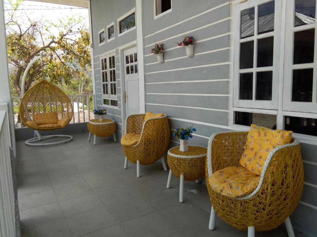 - une terrasse couverte avec des chaises et des tables en osier dans l'établissement J-Rima Homestay Borong, à Wado