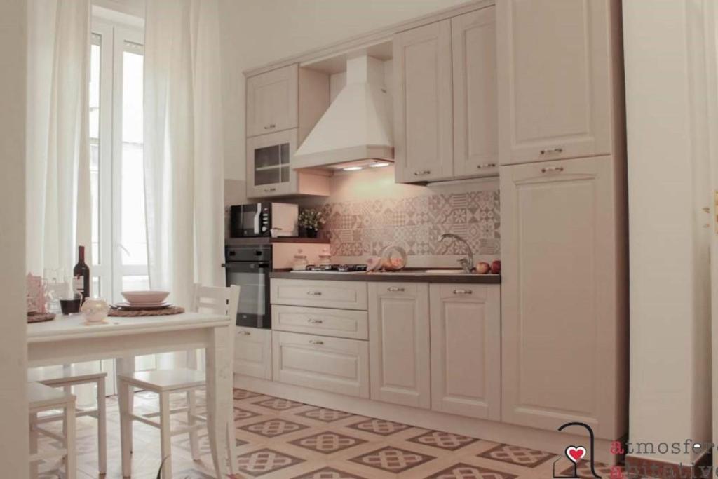una cocina con armarios blancos, una mesa y una barra en CASACRIZIA en Cagliari