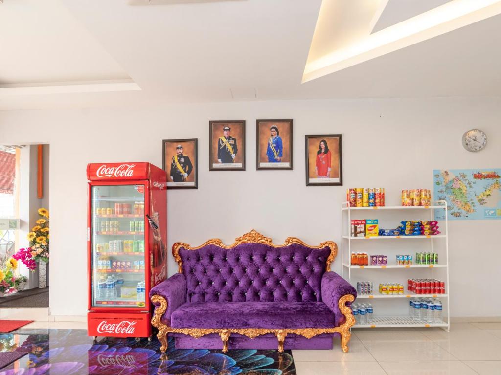 a living room with a purple couch and a cocacola at Zenz Hotel in Kulai