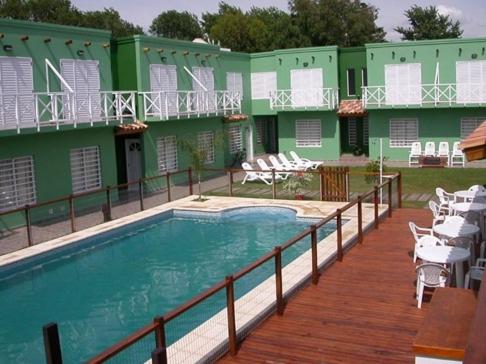 a building with a pool and a deck with chairs at Complejo Hueney in Mar de Ajó