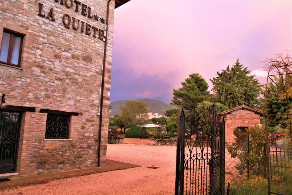 um velho edifício de tijolos com um portão em frente em Hotel La Quiete em Assisi