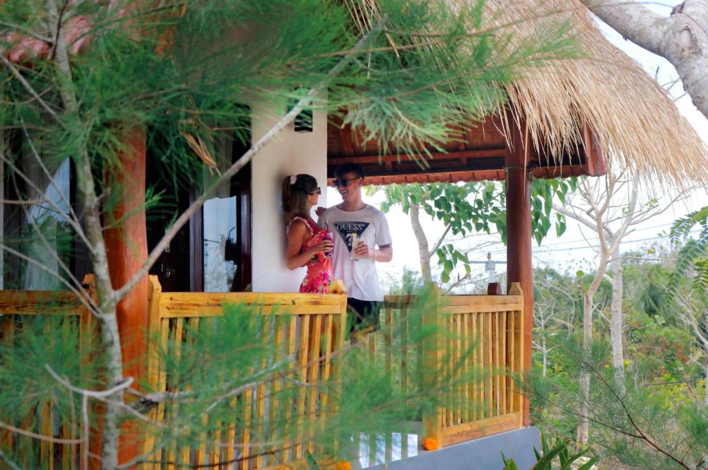 een man en een vrouw die op een veranda van een huis staan bij Temeling Jungle Inn in Nusa Penida