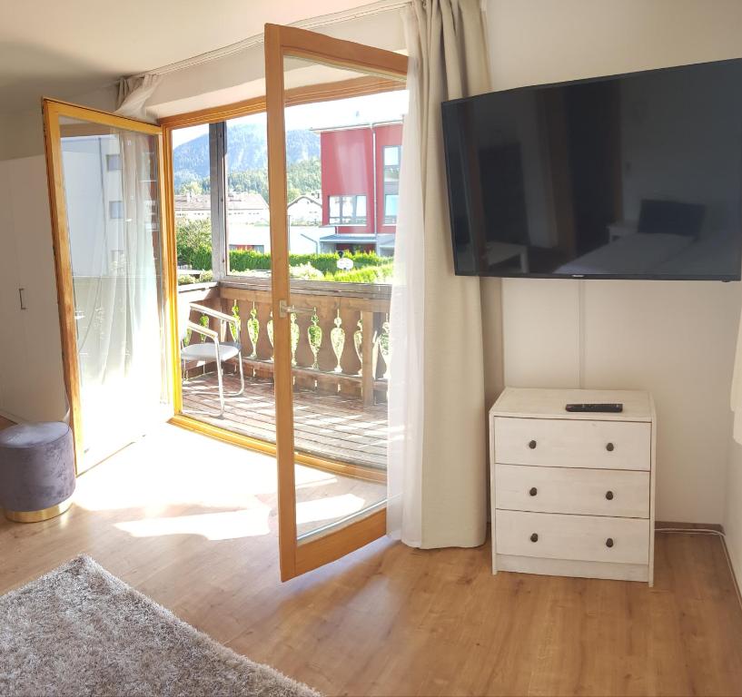Zimmer mit einem TV, einer Kommode und einem Balkon in der Unterkunft Füssen Apartments - West Apartments in Füssen