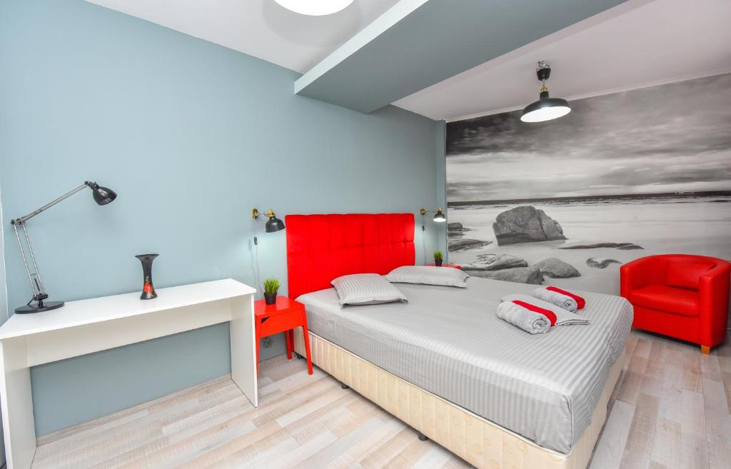 a bedroom with a bed and a red chair at City Center Suite With Terrace in Bucharest