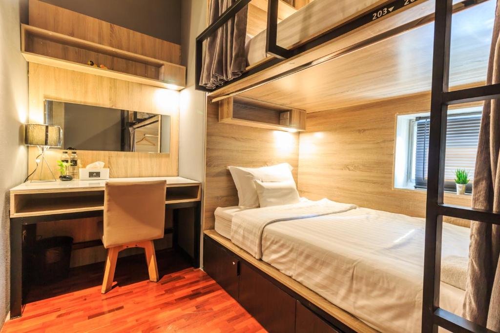 a bedroom with a bed and a desk and a mirror at To Bed Poshtel in Chiang Mai