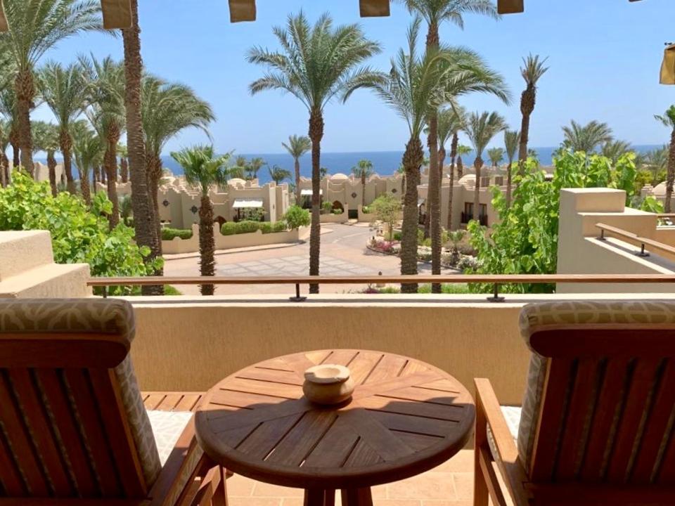 Elegant Apartment in a Luxury Resort في شرم الشيخ: طاولة وكراسي على شرفة مع أشجار النخيل