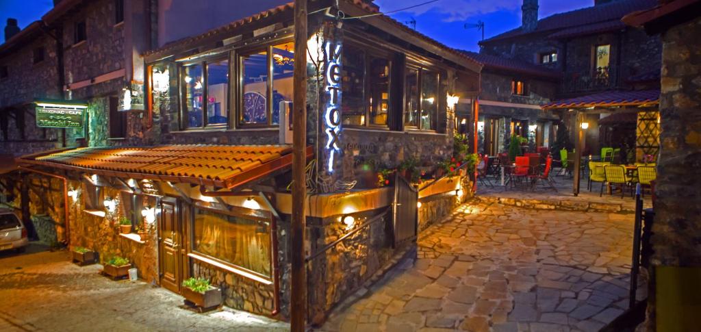 a building with lights on a street at night at METOHI INN in Palaios Agios Athanasios