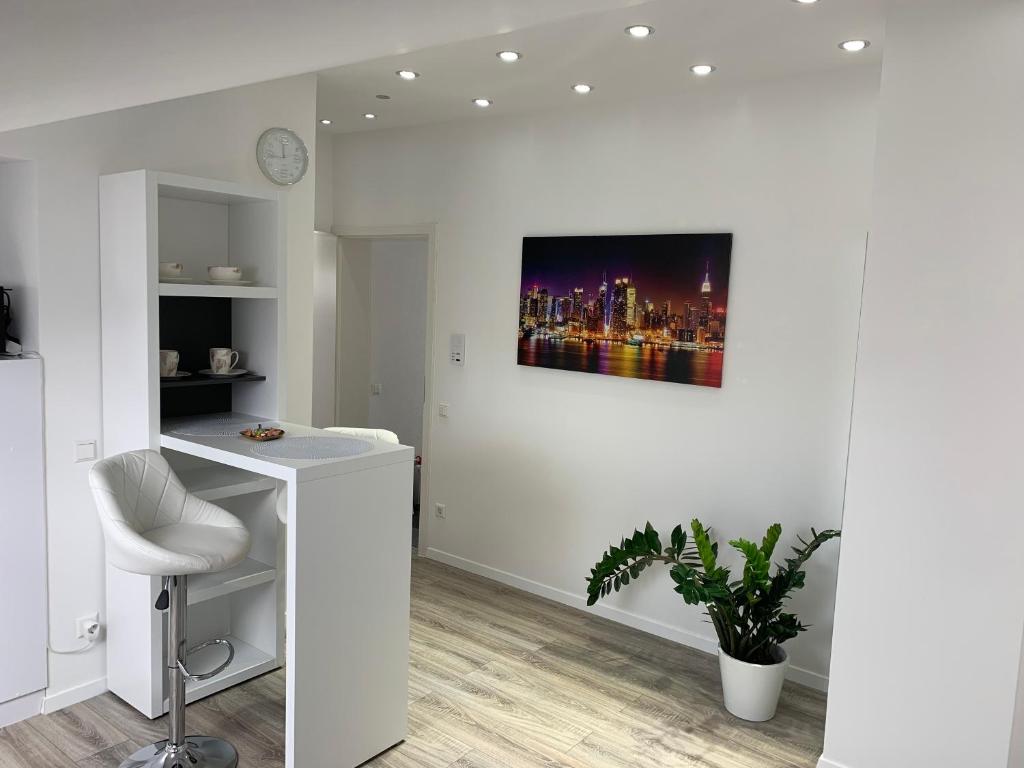een witte kamer met een bureau en een foto aan de muur bij Prime Host apartments in Karlsruhe