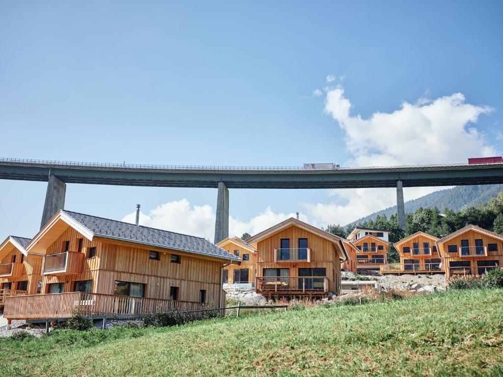 um grupo de casas de madeira com um comboio numa ponte em Cozy Chalet in Steinach am Brenner with Balcony and sauna em Steinach am Brenner