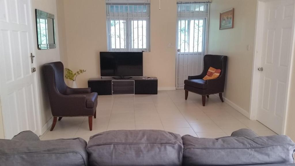 ein Wohnzimmer mit einem Sofa, 2 Stühlen und einem TV in der Unterkunft Campeche Villa Jasmine Apartment in Méro