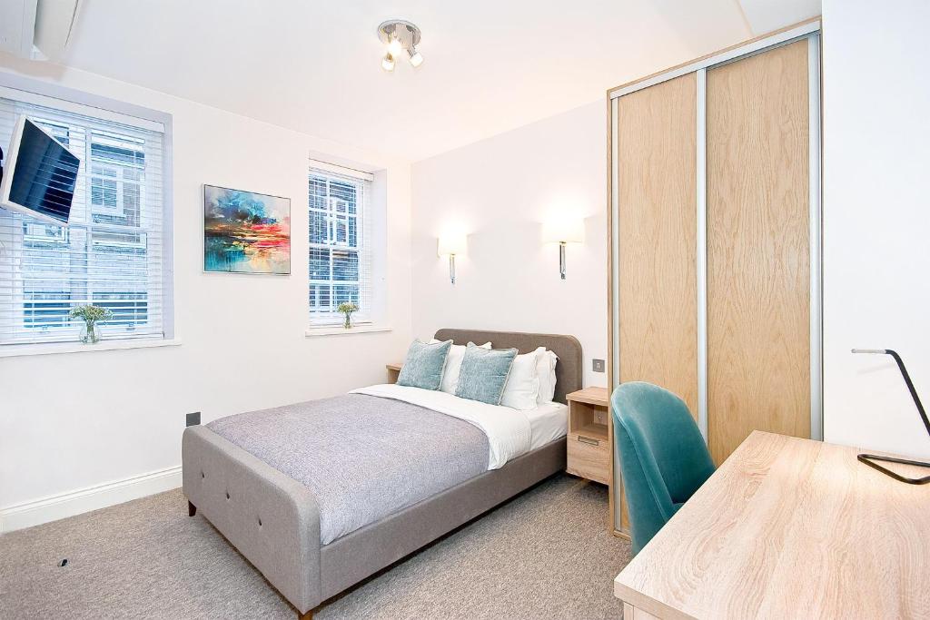 - une chambre avec un lit, un bureau et des fenêtres dans l'établissement Eldon Chambers Pod 6 by City Living London, à Londres