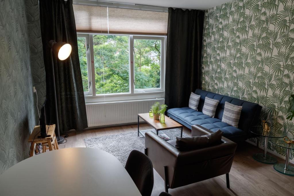 een woonkamer met een blauwe bank en een tafel bij CityTreeHouse ApartHotel in Arnhem
