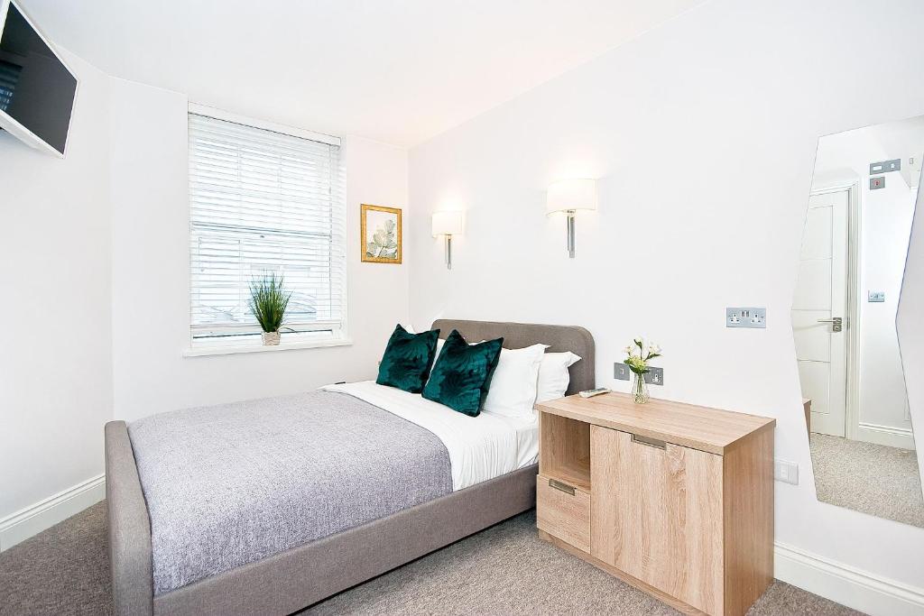 a white bedroom with a bed with green pillows at Eldon Chambers Pod 4 by City Living London in London