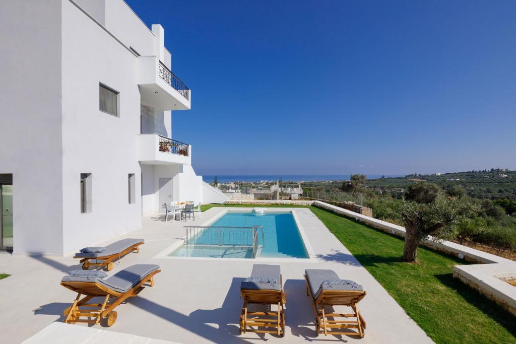a villa with a swimming pool and lounge chairs at Apartment Tilio - New apartment with private pool 1400m from the beach in Rethymno Town