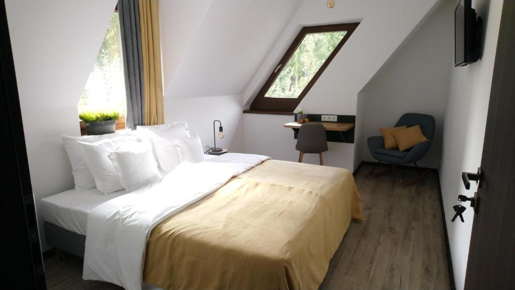 a bedroom with a bed with white sheets and a window at Willowa Chata in Dzianisz