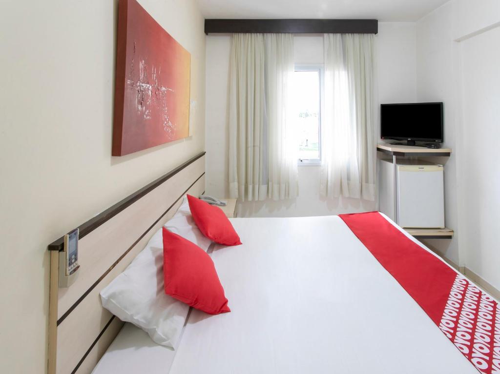 1 dormitorio con 1 cama blanca grande con almohadas rojas en Polo Hotel, en São José dos Campos