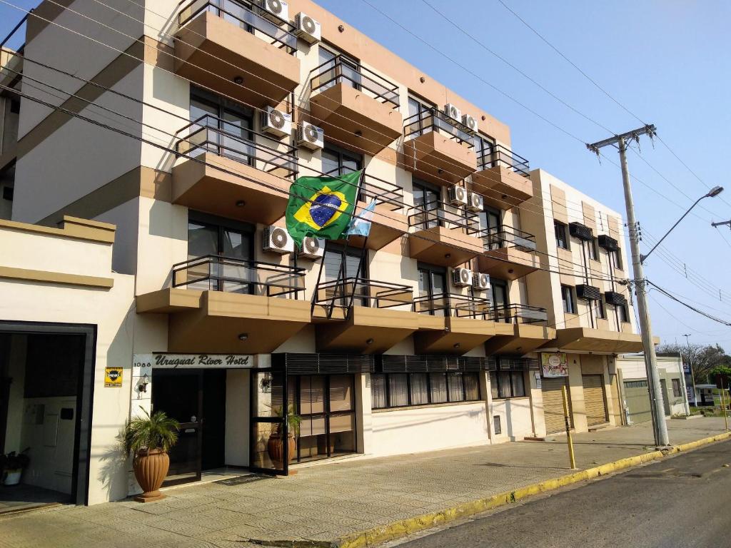 um edifício com uma bandeira ao lado em River Hotel em Uruguaiana