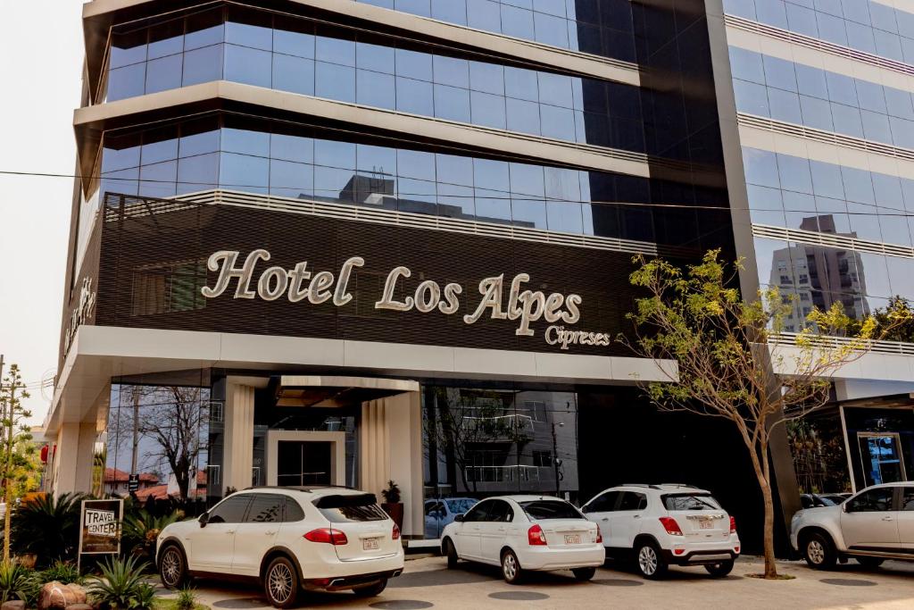 a building with cars parked in front of it at Hotel Los Alpes Cipreses in Asunción