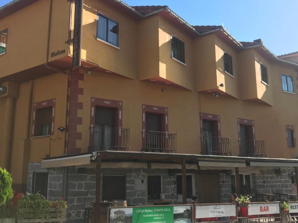 un gran edificio amarillo con ventanas y balcones en Hotel Rural El Alberche, en Burgohondo