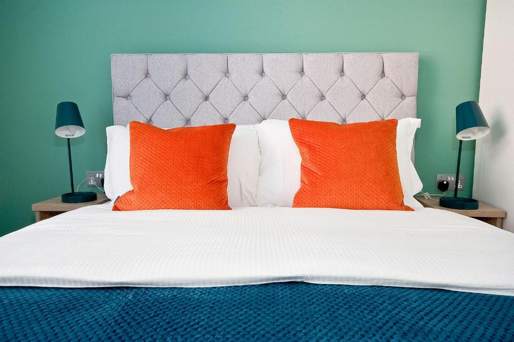 a bedroom with a large bed with orange pillows at Interlude House A by City Living London in London