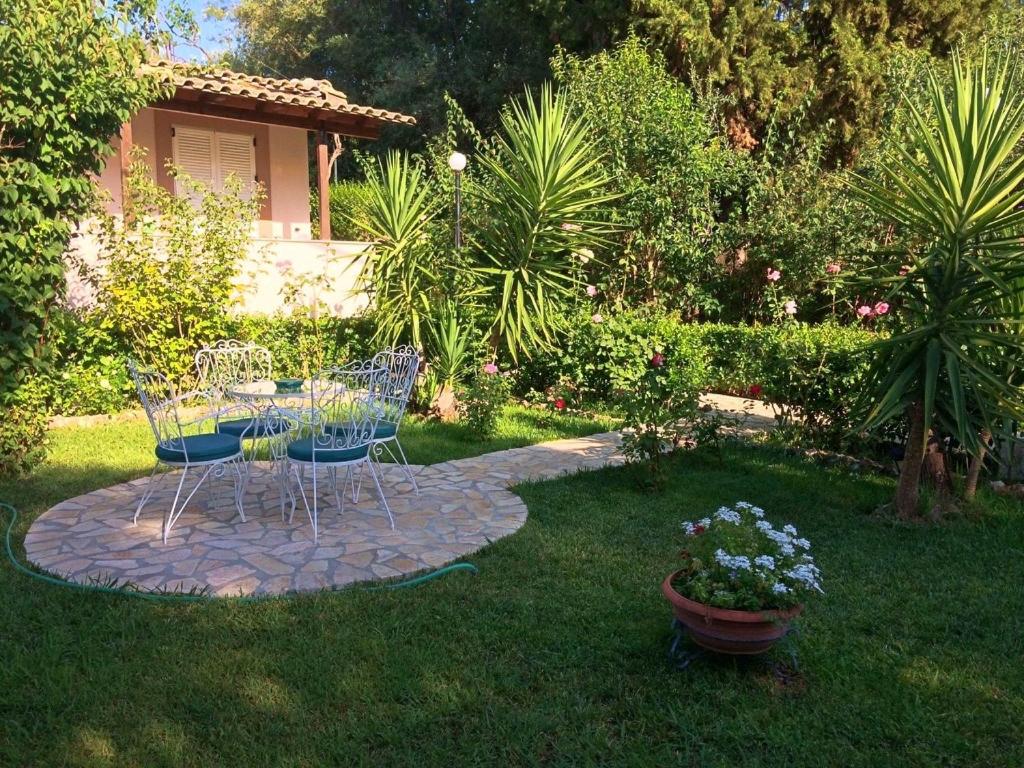 a garden with two chairs and a table in the grass at TO PATRIKO - APARTMENTS FOR RENT in Igoumenitsa