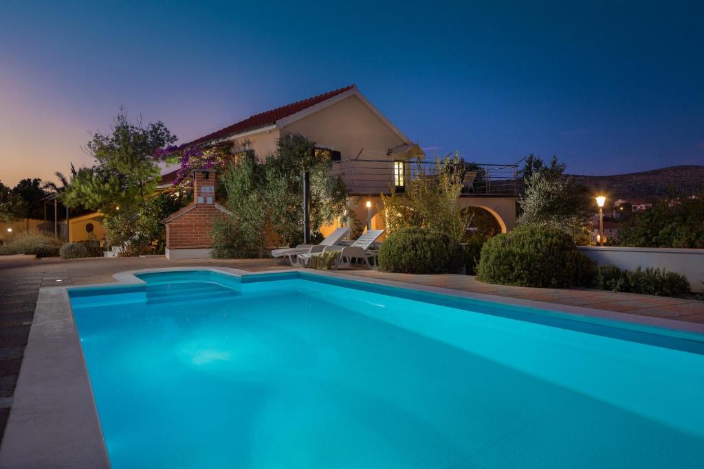 a swimming pool in front of a house at night at Villa Bravura Milna Brac in Milna