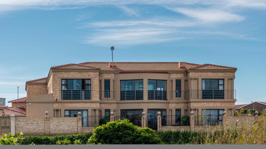 a large house with a balcony on top of it at Dolphin Dance Lodge in Port Elizabeth