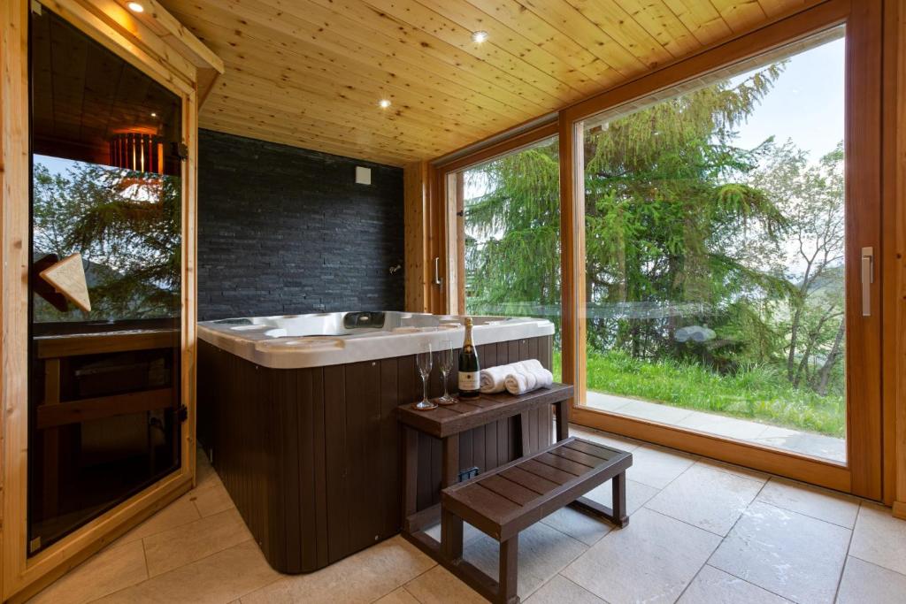 a bathroom with a large tub and a window at Jacuzzi & Sauna | Chalet Teremok in La Tzoumaz