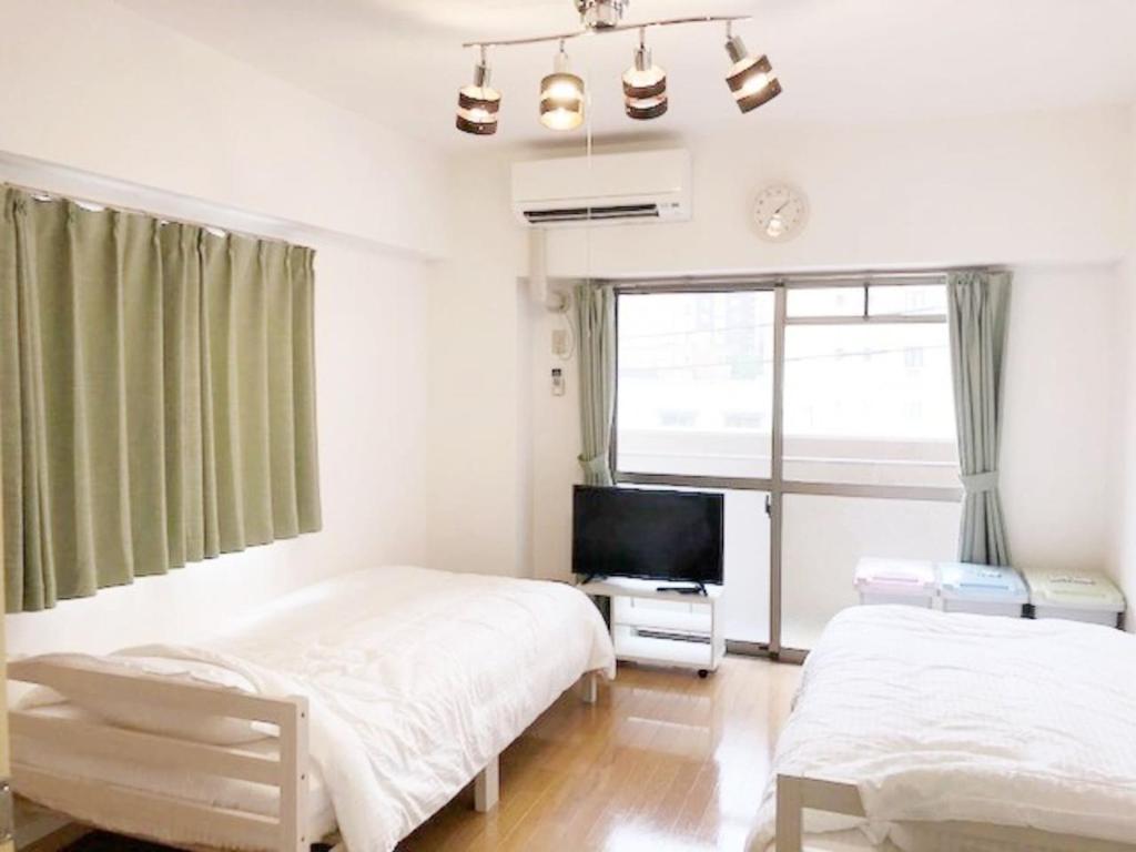 1 dormitorio con 2 camas y TV. en ピオーレ大手門402, en Fukuoka