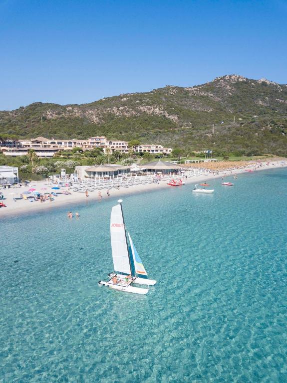 a small sail boat in the water near a beach at Hotel Abi d'Oru in Porto Rotondo