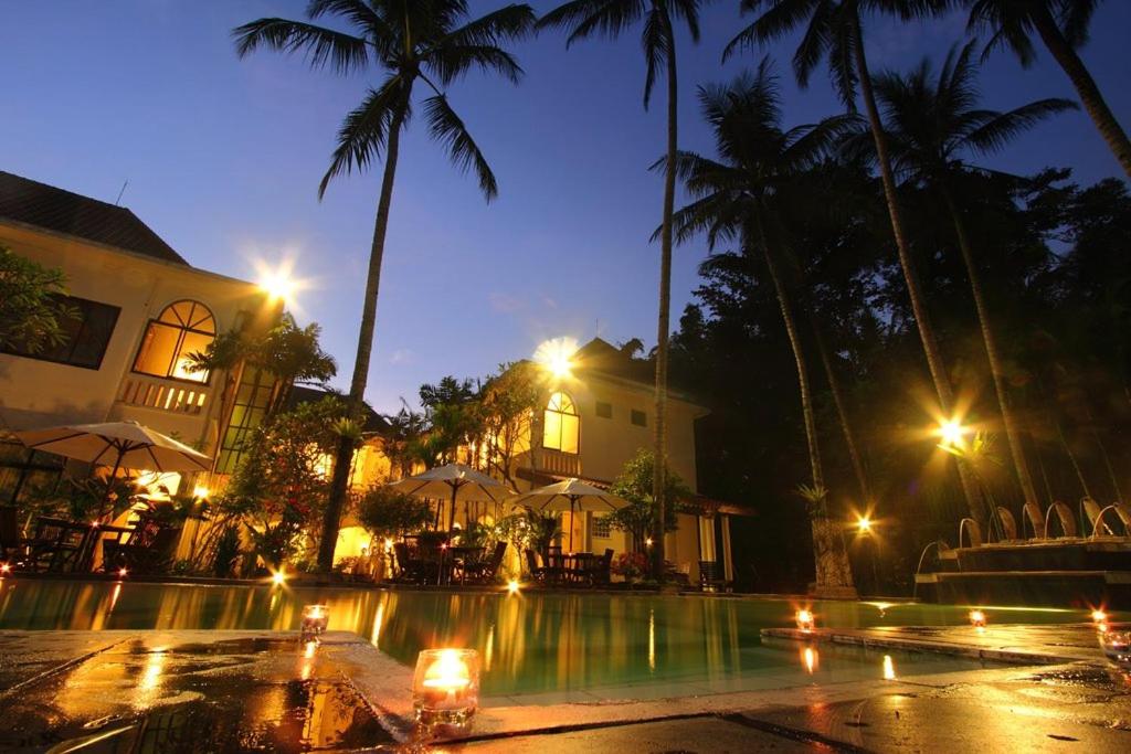 a resort with a pool at night with palm trees at Sarasvati Borobudur in Borobudur