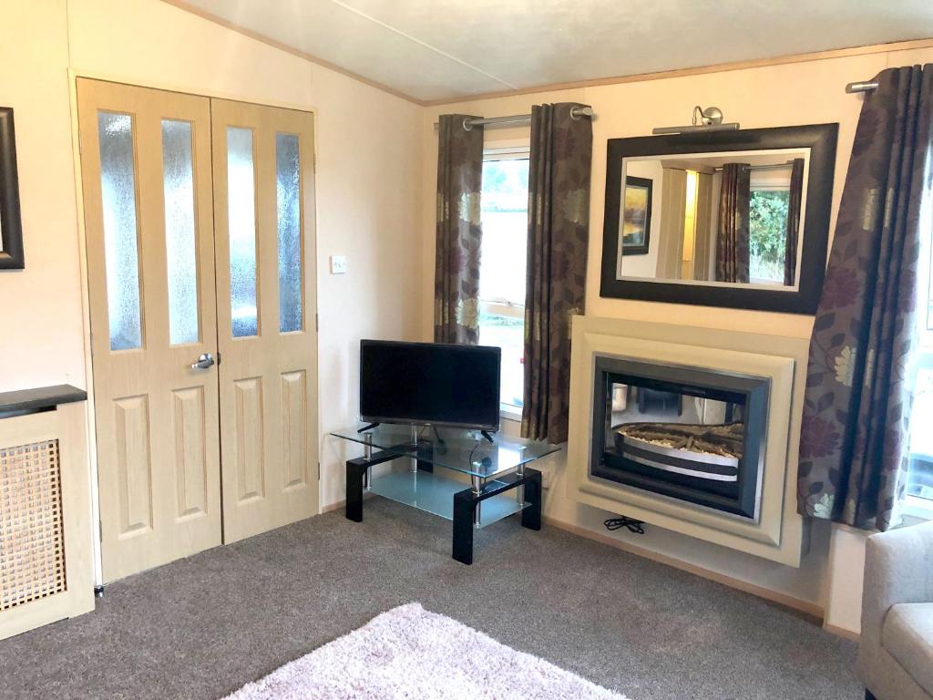 a living room with a television and a fireplace at Gold Standard Caravan on South View Park in Skegness
