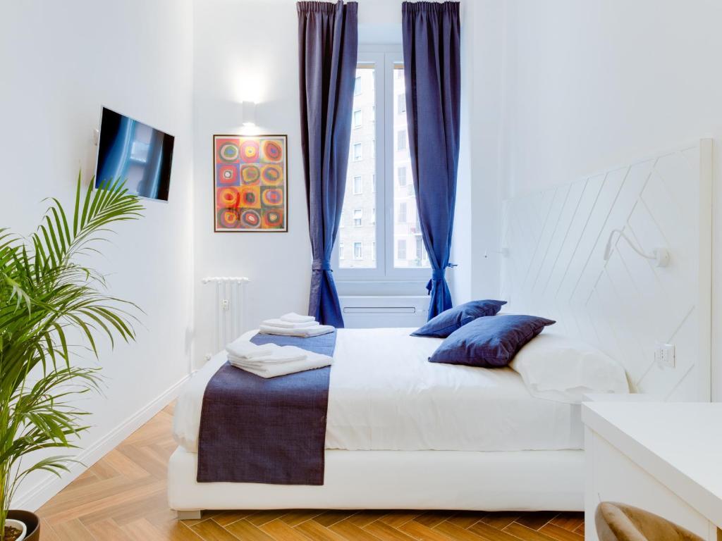 ein weißes Schlafzimmer mit einem Bett mit blauen Kissen in der Unterkunft The Right Place - Guest House in Rom