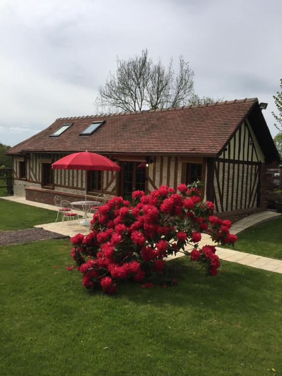 ein Haus mit einem Busch voller roter Blumen davor in der Unterkunft Les Hortensias in Le Fournet